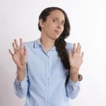 woman shying away with both hands up and uncomfortable expression