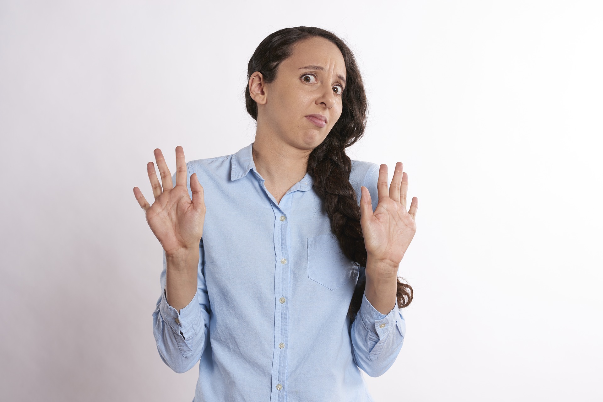 woman shying away with both hands up and uncomfortable expression
